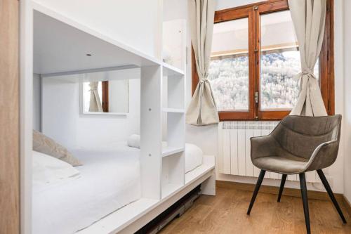 a bedroom with a white bunk bed and a chair at Relax en Pirineo l Vistas l Wifi l Balcón in Panticosa