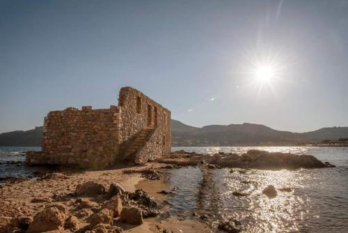 an old building on the shore of a body of water at Seaside Plitra Paradiso - Steps from the Beach in Plytra