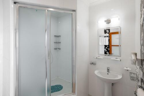 a white bathroom with a shower and a sink at Kazka in Zatoka