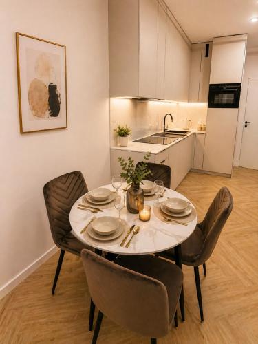 a dining room table with chairs and a kitchen at Ceglana Apart 01A in Katowice