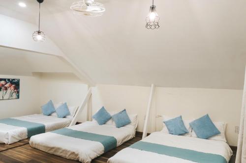three beds in a room with blue pillows at StayDalat in Ấp Ða Lợi