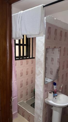 a pink bathroom with a sink and a shower at The 4 Kays Apartment - One Bedroom in Agege