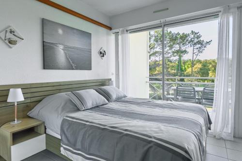 a bedroom with a bed and a large window at Entre Foret et Ocean in Moliets-et-Maa
