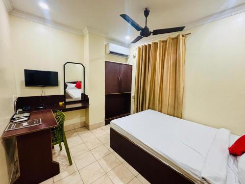 a bedroom with a bed and a desk and a computer at HOTEL SHIVA in Guwahati
