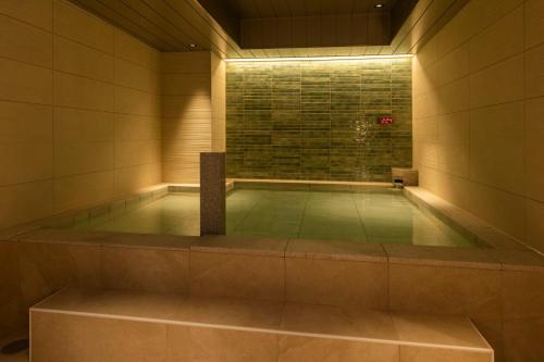 ein Schwimmbad in einem Gebäude mit einer gefliesten Wand in der Unterkunft Hotel Global View Iwaki in Iwaki