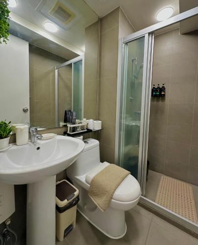 a bathroom with a toilet and a sink and a shower at Knightsbridge Residences in Manila