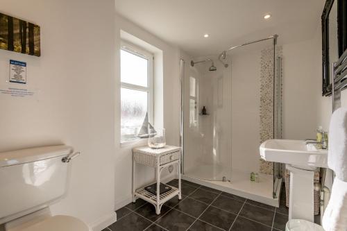 a white bathroom with a shower and a sink at Driftwood - Pittenweem in Pittenweem