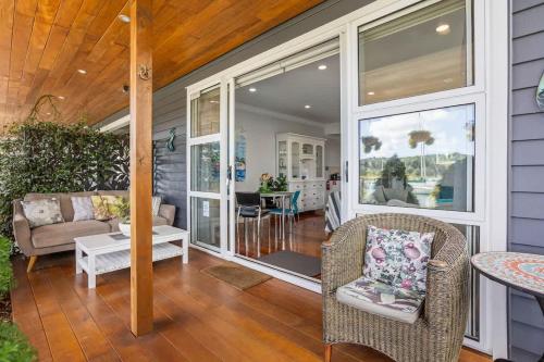 a screened in porch with chairs and a table at The Weiti Waterfront in Whangaparaoa