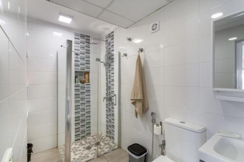 a white bathroom with a shower and a toilet at Rainbow Amadores in Mogán