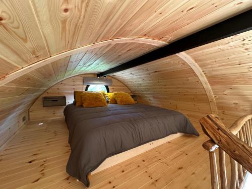 a bed in a room with a wooden ceiling at Scranton luxury fishing pod with private fishing Jetty in Spilsby