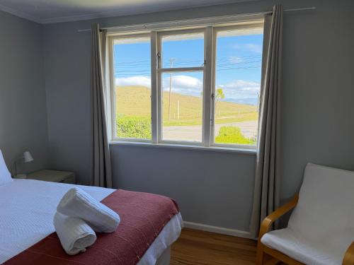 a bedroom with a window and a bed and a chair at Tyne above Town in Oamaru