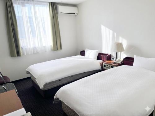 a hotel room with two beds and a window at ビジネスホテル圭 in Kimiidera