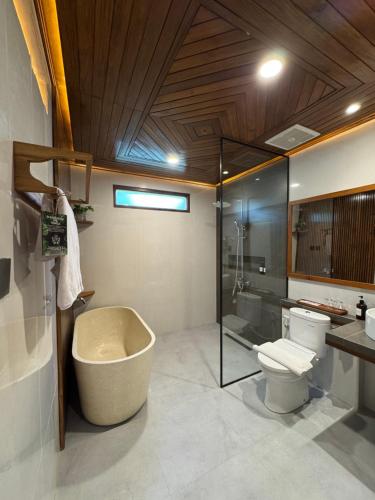 a bathroom with a tub and a toilet and a sink at Casa Kandara in Waingapu