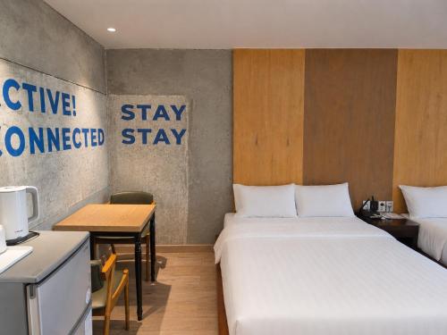 ein Zimmer mit zwei Betten, einem Tisch und einer Küche in der Unterkunft Vengastay in Seogwipo