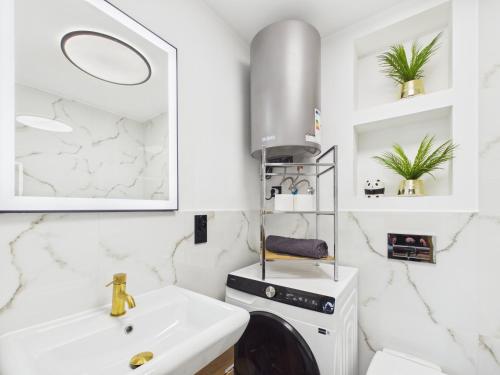 a white bathroom with a sink and a washing machine at Apartamenty Retro Loft in Chorzów