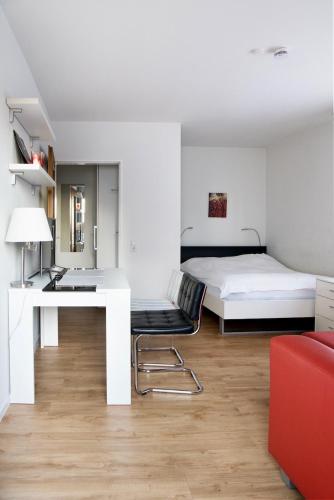 a white bedroom with a desk and a bed at Hotel Wintersmühle in Bielefeld