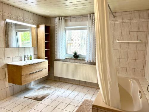 a bathroom with a tub and a sink and a window at Gästehaus Trockau in Pegnitz