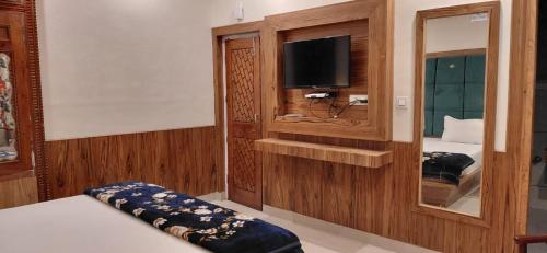 a bedroom with a bed and a tv and a mirror at Monal Homestay in Kulu