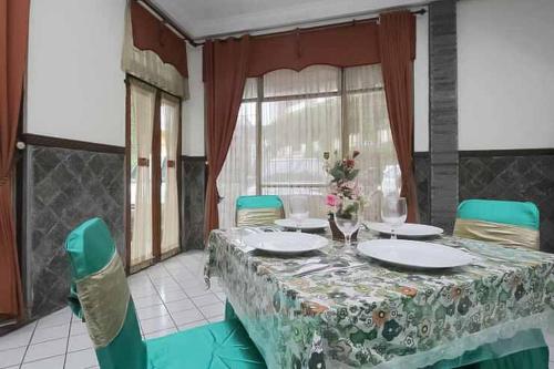 a dining room with a table and green chairs at Hotel Lestari Near Lippo Plaza Mall Jember in Jember