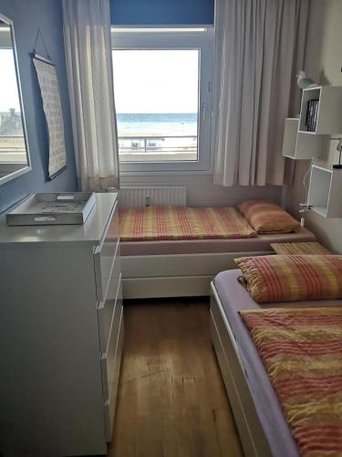 a bedroom with two beds and a desk and a window at Strandhotel Wohnung 16 in Dahme