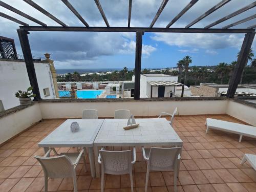a white table and chairs on a patio with a pool at Messapia Hotel in Marina di Leuca