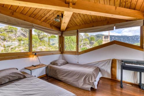 two beds in a room with windows and a piano at Villa dans Site Exceptionnel in Mourèze