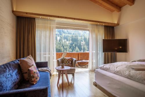 a bedroom with a bed and a couch and a window at Hotel zur Pfeffermühle in Sankt Anton am Arlberg