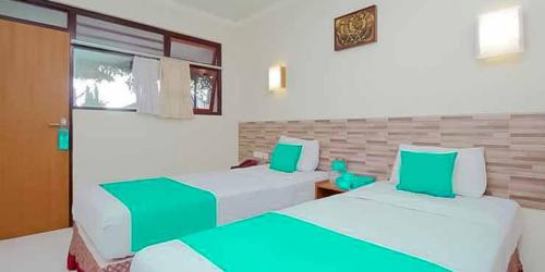 two beds in a room with green and white at Hotel Lestari Near Lippo Plaza Mall Jember in Jember