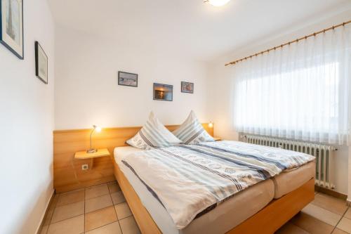 a small bedroom with a bed and a window at Ferienwohnung Bäumer Borkum - Nichtraucher & allergikerfreundlich in Borkum