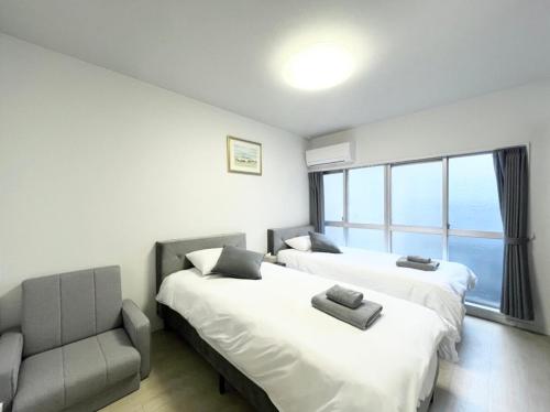a bedroom with two beds and a chair and a window at Hotel Suite 2 in Warabi