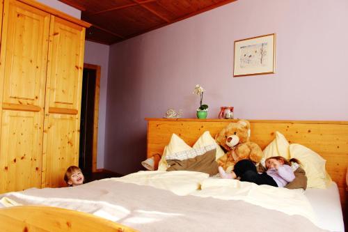 two children laying on a bed with a teddy bear at Da Bräuhauser in Stadl an der Mur