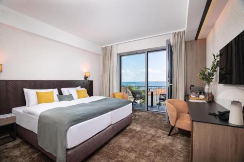 a hotel room with a bed and a desk and a window at Montello Hotel in Balatonfüred