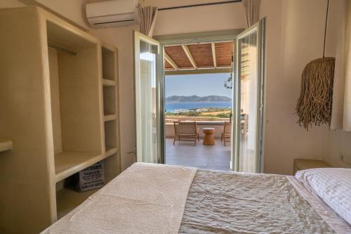 a bedroom with a bed and a view of the ocean at Small Cyclades Houses in Koufonisia