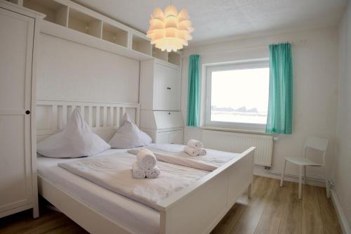 a bedroom with a large white bed with towels on it at England 5 in Nordstrand