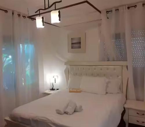 a bedroom with a white bed with two towels on it at אצל דניאל במושבה - 2 צימרים מושלמים עם נוף לכינרת in Kinneret