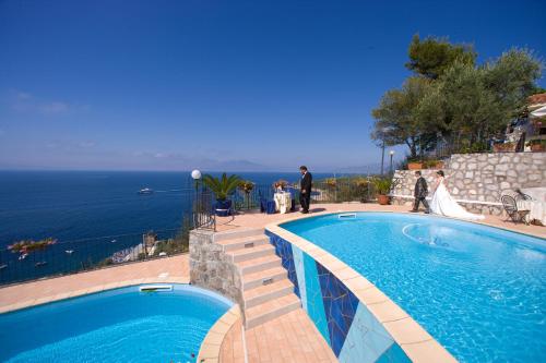 a bride and groom standing next to a swimming pool at Villaggio Villa Lubrense in Massa Lubrense