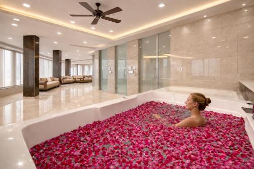 a woman laying in a bath tub covered in pink flowers at Hotel The Prithvi Delhi Airport With Free Airport Pic Up in New Delhi
