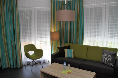 a living room with a green couch and a table at Gästehaus Wilhelmshöhe in Butzbach
