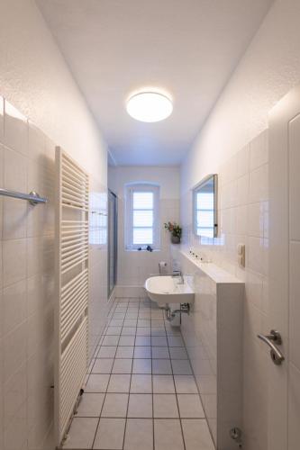 a white bathroom with a sink and a mirror at FeWo-Ahrenshoop in Prerow
