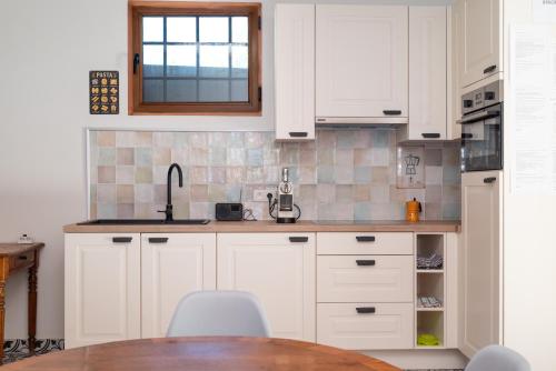 a kitchen with white cabinets and a wooden table at Stientjeshof "Het Paardenhuisje & Hooihuys " in Sint-Lievens-Houtem