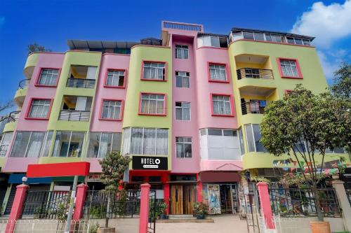 a pink and yellow building with a sign on it at Super Hotel O Sankaradeva Kalakshetra Formerly HK Residency in Dispur