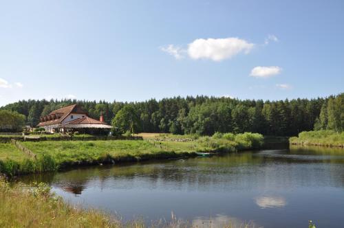 a river with a house in the middle of a field at Pensjonat Dolina Wierzby in Olsztyn