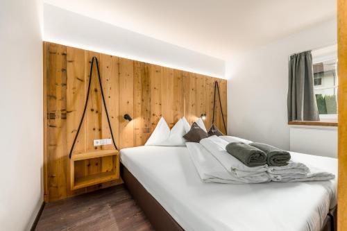 a bedroom with a white bed with a wooden wall at Bergheim Plose - Appartements in St Andrä bei Brixen in Bressanone