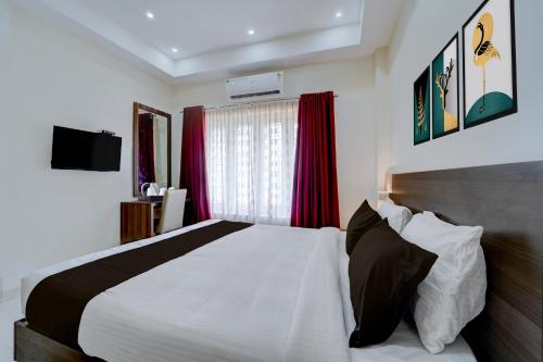a bedroom with a large white bed and red curtains at Super Collection O RTO Office Uzhavoor Formerly Hotel Zodiac in Puduveli