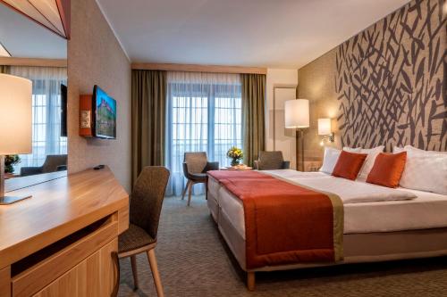 a hotel room with a bed and a desk at Ensana Thermal Aqua in Hévíz