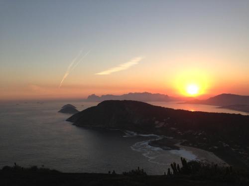 a sunset over a small island in the ocean at Vila Ebert in Niterói