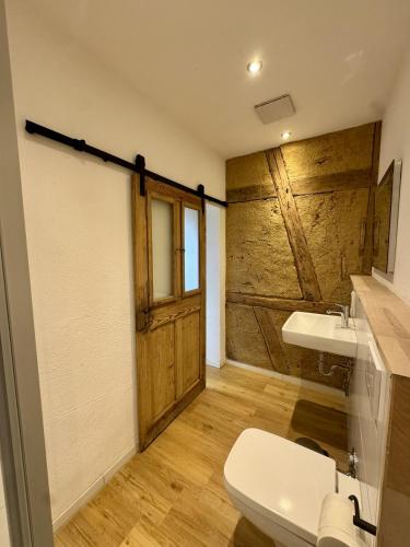 a bathroom with a toilet and a wooden door at Ferienscheune Rheingoldhof in Sankt Goar