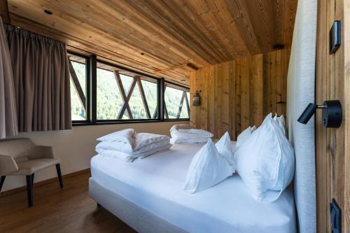 a bedroom with a bed with white pillows on it at Amus Suites Dolomites in Anterselva di Mezzo