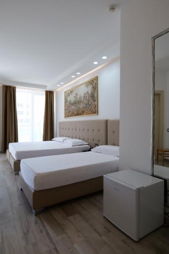 a bedroom with three beds and a painting on the wall at Hotel Mille Amici in Shëngjin