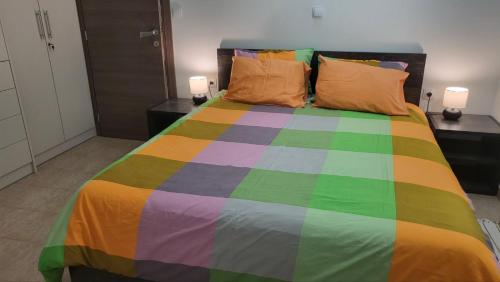 Ein Schlafzimmer mit einem farbenfrohen Bett, zwei Tischen und zwei Lampen in der Unterkunft Horizon Corner in Ladochórion